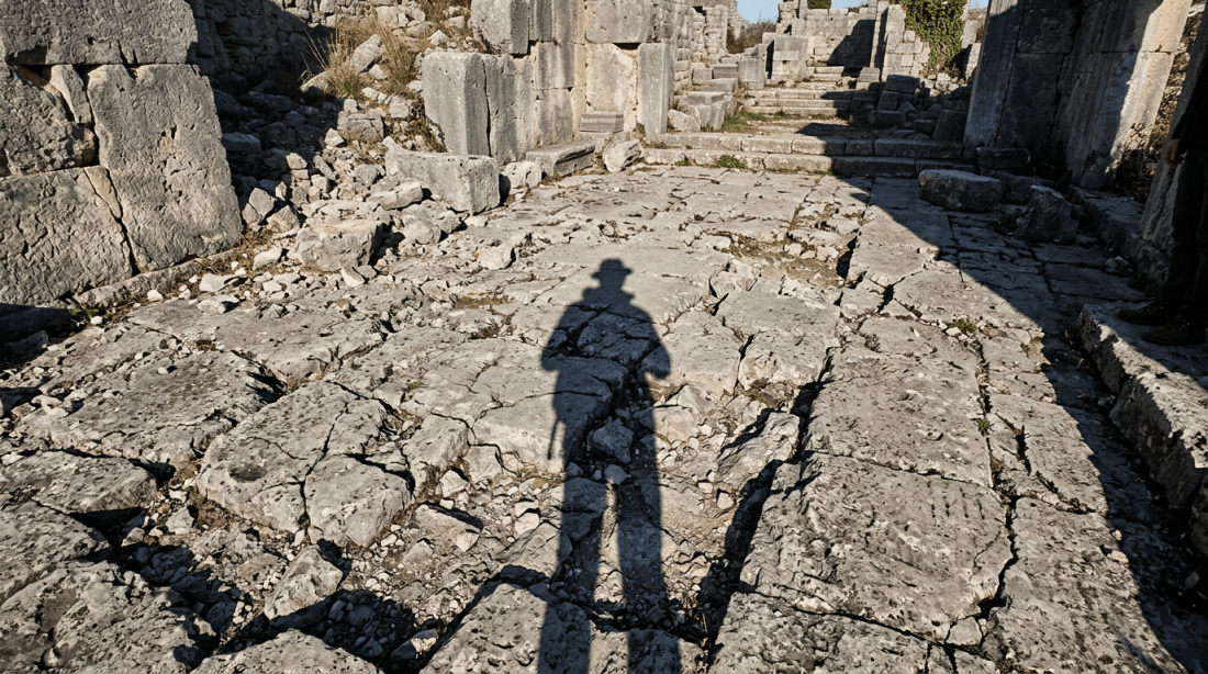 Shadow of a person wearing a hat on cracked stone ruins pathway